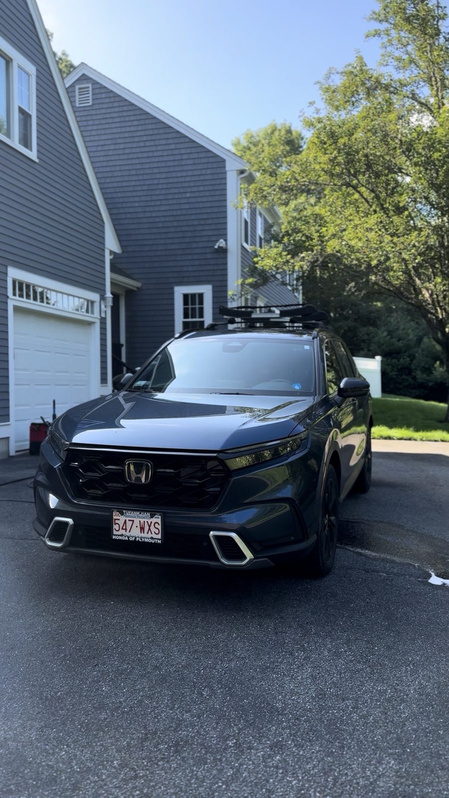 Dark Honda CR-V Sport Touring hybrid sitting in a driveway with a freshly coated, glossy finish