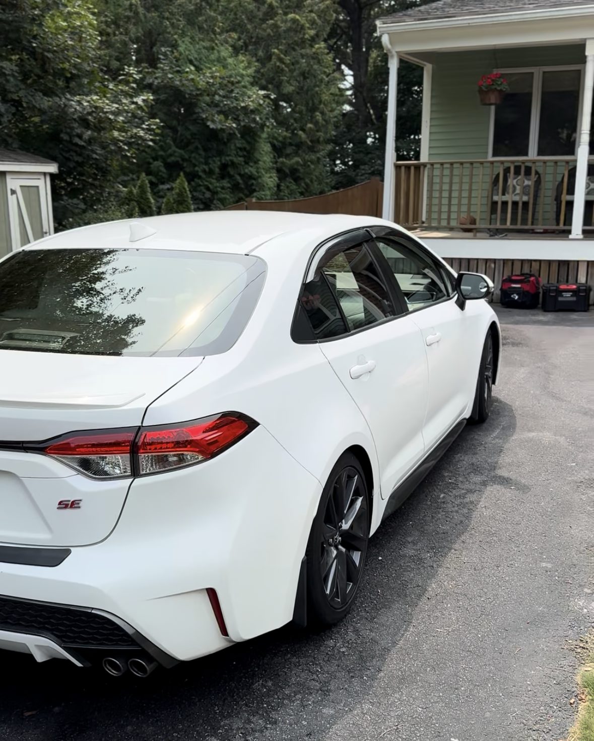 White Toyota Corolla SE with gloss black wheels parked in a driveway after detailing